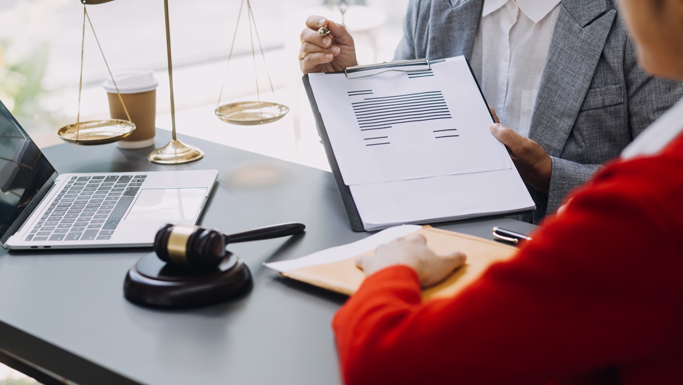Business and lawyers discussing contract papers with brass scale on desk in office. Law, legal services, advice, justice and law concept picture with film grain effect
